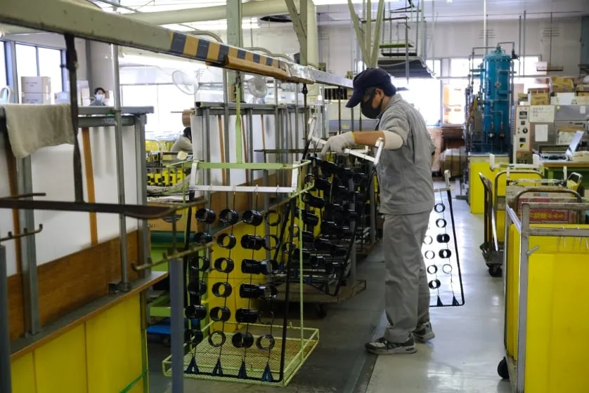 治具に掛けた製品を工場内で運ぶ作業員